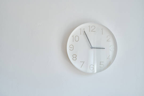 istock White round wall clock hanging on the wall. A minimalistic image of a wall clock on a white background with copy space. Scandinavian style in the room 1332531803