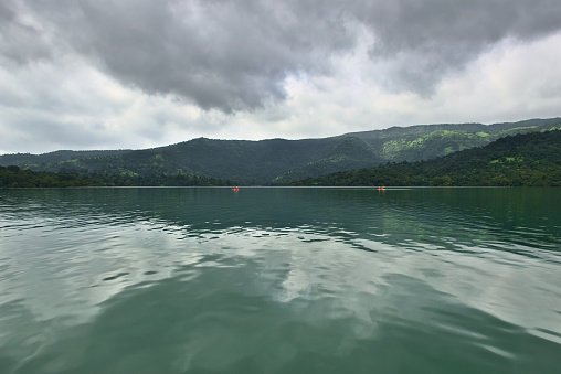 Stunning panoramic landscape view of beautiful Koyna dam backwaters on a cloudy day with kayakers at Tapola, which is also known as Mini Kashmir of Maharashtra in India.