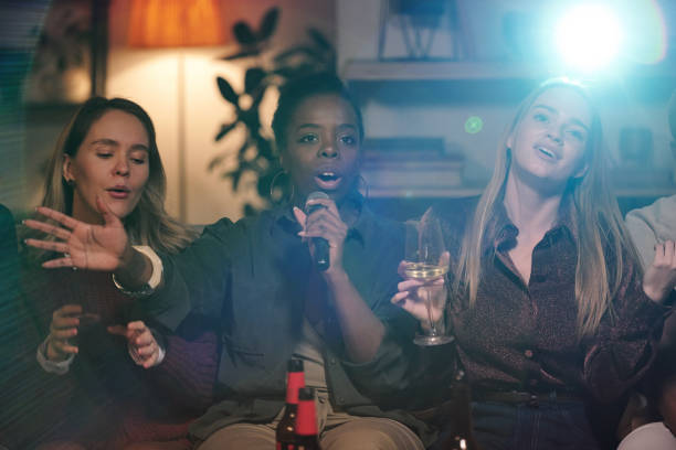 istock Group of young intercultural friends singing karaoke while sitting on couch 1332539743