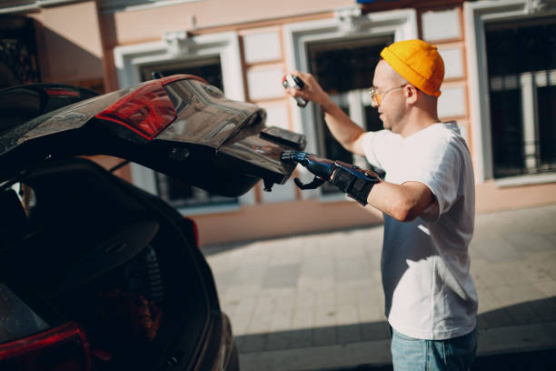 istock Young disabled man with artificial prosthetic hand closing back trunk of car 1332541001