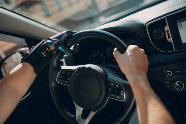 istock Young disabled man driver with artificial prosthetic hand driving vehicle car. 1332541003