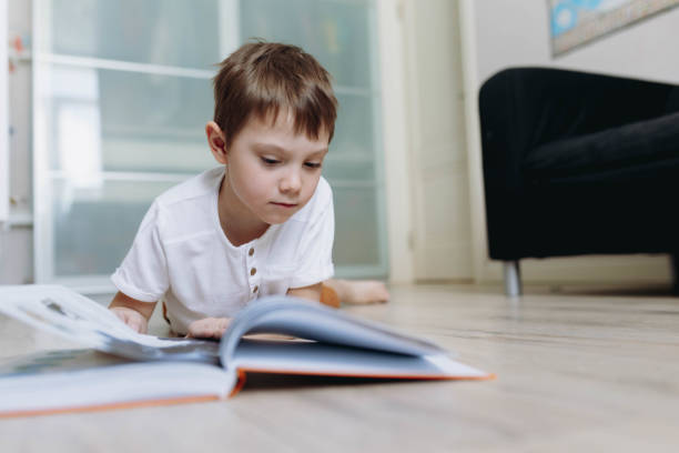 istock A boy is reading a book on the floor at home. Image with selective focus 1332542003