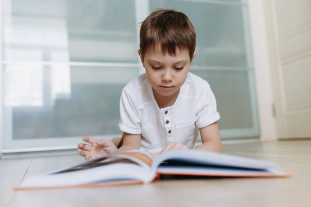 istock A boy is reading a book on the floor at home. Image with selective focus 1332542327