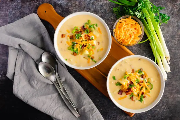 Creamy potato soup garnished with sour cream, shredded cheese, bacon bits, and chives