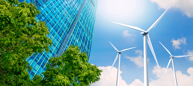 Los edificios modernos de gran altura están alimentados por turbinas eólicas y naturaleza verde. photo