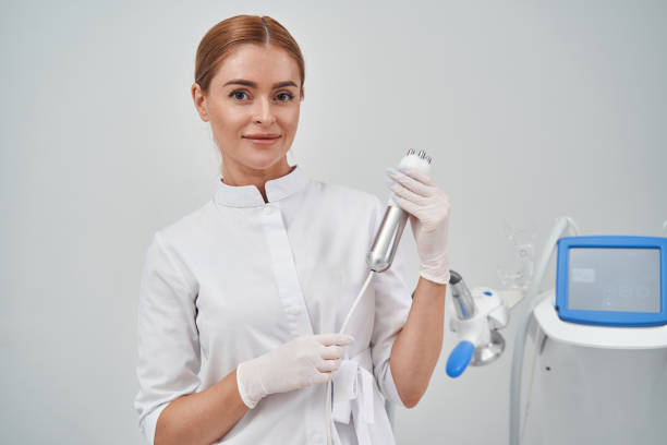 Gappy cure lady enjoying work in massage studio Waist up portrait of smiling young woman in uniform holding equipment for massage in her office Dental Cleanings stock pictures, royalty-free photos & images