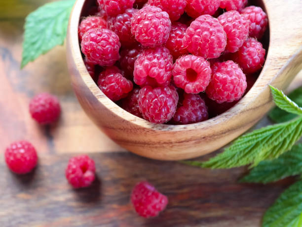 istock Wooden cup with wild raspberries 1332550890