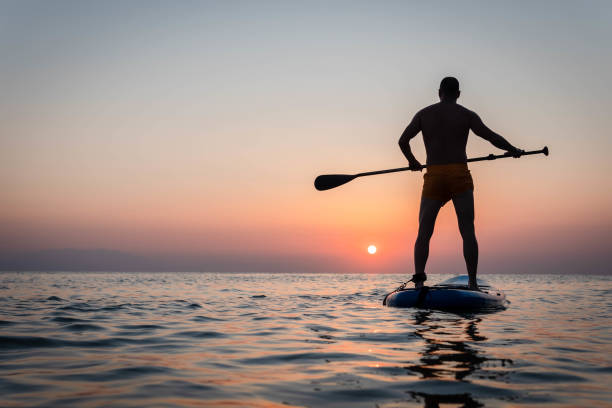 istock Silhouette of man paddleboarding at sunset 1332555289