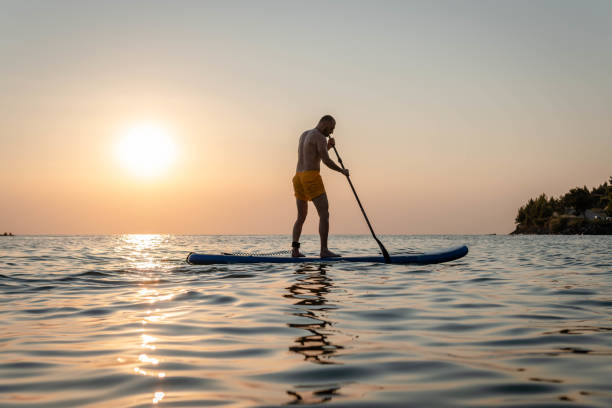 istock Silhouette of man paddleboarding at sunset 1332555313