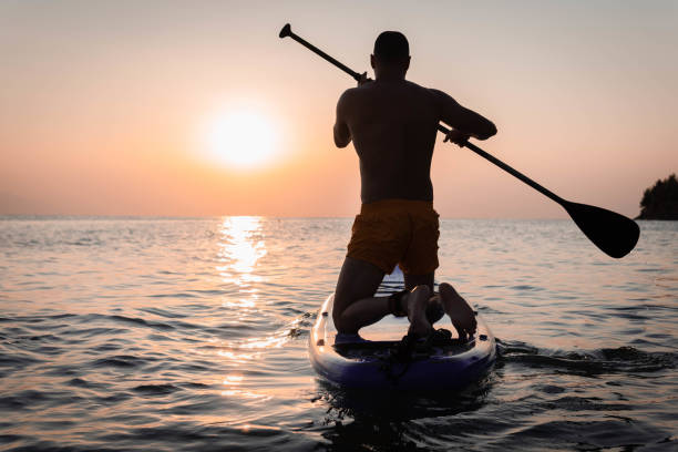 istock Silhouette of man paddleboarding at sunset 1332555348