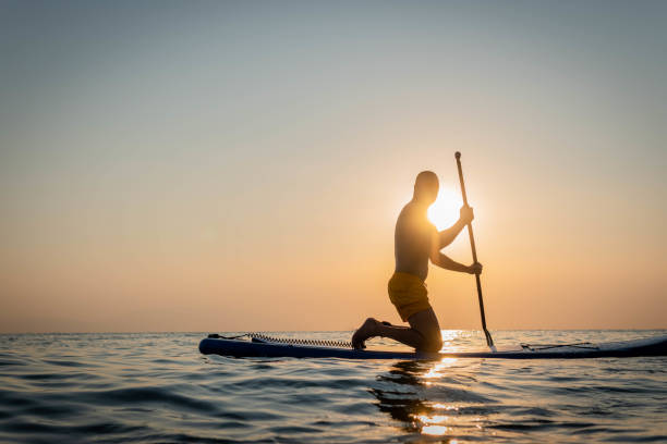istock Silhouette of man paddleboarding at sunset 1332555368