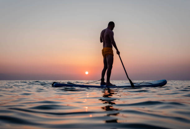 istock Silhouette of man paddleboarding at sunset 1332555447