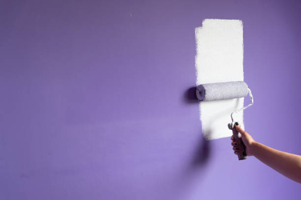 Woman hand painting with roller on big copy space wall stock photo