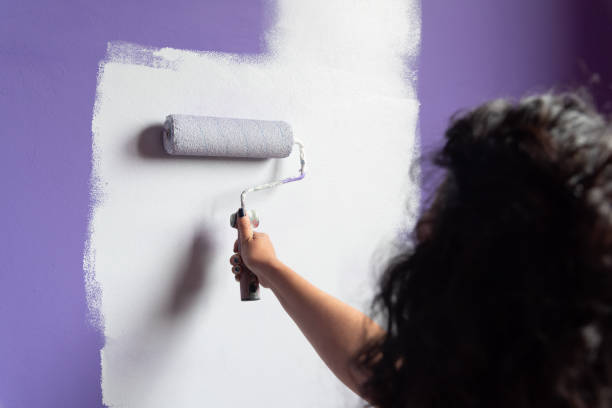 istock Unknown young woman painting home room with roller 1332556756