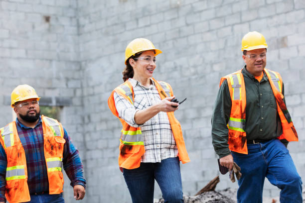 istock Hispanic woman directs construction workers at job site 1332558090