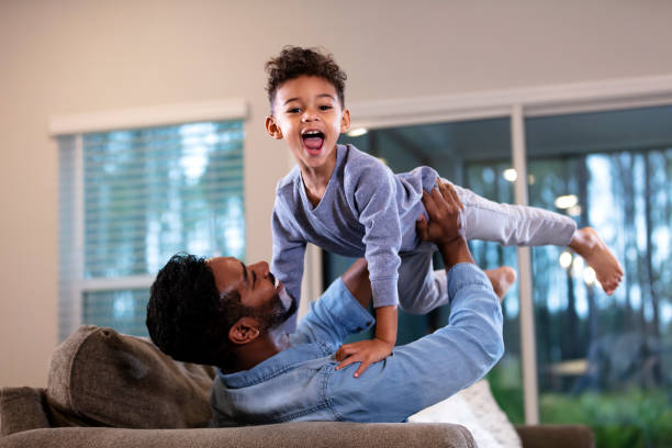 istock Father on sofa holding son up, boy laughing at camera 1332558299