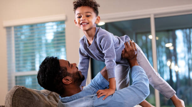 istock Father on sofa holding son up, boy smiling at camera 1332558305