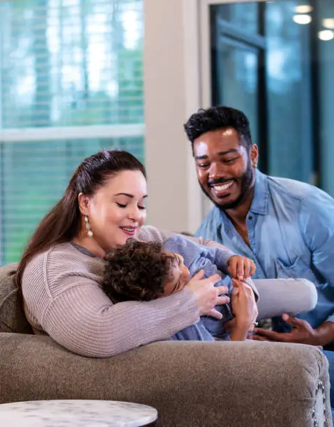 Photo of Multi-ethnic family with boy playing on sofa at home