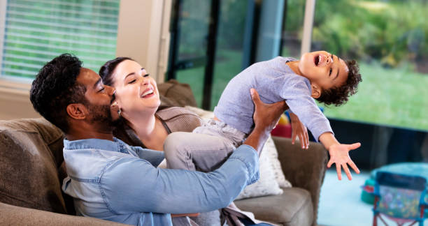 istock Interracial family with boy playing on sofa at home 1332558317
