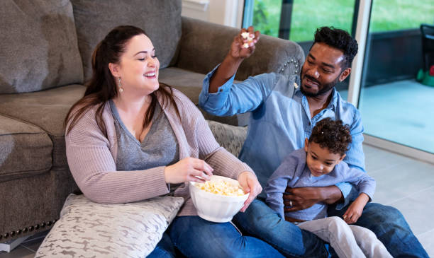 istock Multi-ethnic family watching TV, throwing popcorn 1332558370