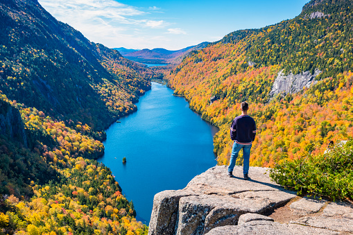 Man enjoys view in the Adirondack Mountains, New York State, USA, during Fall colors.