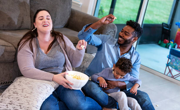 istock Multi-ethnic family watching TV, throwing popcorn 1332558904