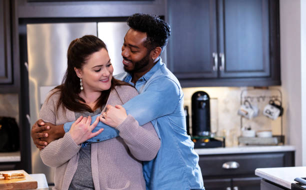 istock Multi-ethnic couple in the kitchen, man hugging woman 1332558914