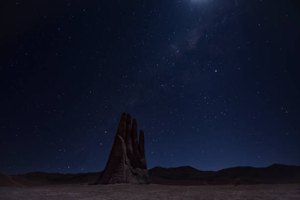 Hand of the desert in Antofagasta, Chile. Night long exposure shot with sky full of stars. Hand of the desert in Antofagasta, Chile. Night long exposure shot with sky full of stars. Moonlight and a shooting star can be seen. atacama region stock pictures, royalty-free photos & images