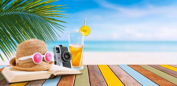 istock fresh orange juice and Beach Accessories On a multi-colored wood Table 1332559869