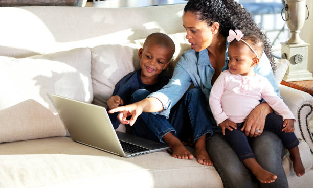 istock Mother with baby on lap, helping son use computer 1332565483