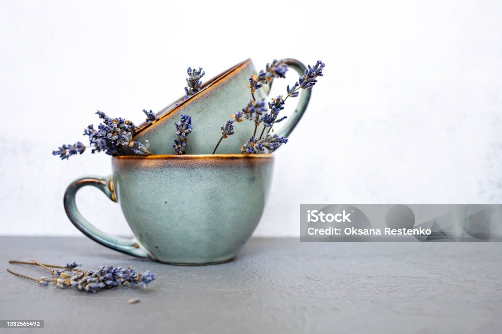 Ceramic cups with dry lavender flowers on gray background.Side view, space for text. Beautiful table setting. Ceramic cups with dry lavender flowers on gray background. Side view, space for text. Beautiful table setting. Tea Cup Stock Photo