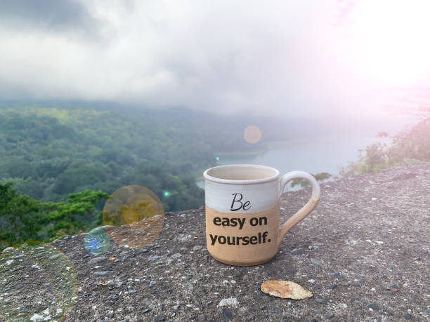 istock Tea cup with message - Be easy on yourself. On nature mountain and lake background. 1332566760