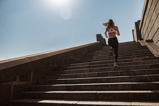 istock Sportive lady in tracksuit runs up old stone steps under clear sky 1332568416