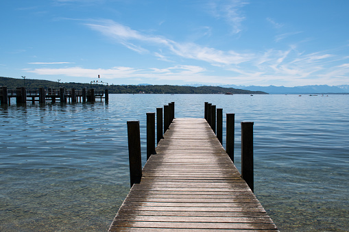 Wooden jetty projecting into Lake Starnberg in Starnberg in Bavaria, Germany, on a sunny summer day.