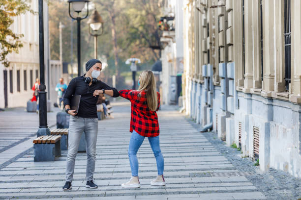 istock Two Casually Dressed Persons are Keeping Social Distancing and Greeting with Elbows. 1332573651