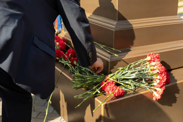 istock A hand puts carnations on the memorial. 1332578567