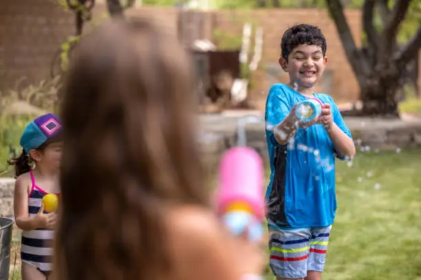 High quality stock photos of family kids playing in the sprinkler and having a squirtgun fight.
