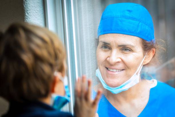 istock Mature Healthcare worker posing seeing her son with a window glass separating them to avoid possible contagion 1332584389