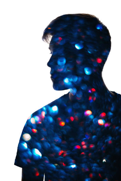 A silhouetted figure is illuminated by vibrant red, green, and blue lights, creating overlapping, abstract shadow effects.