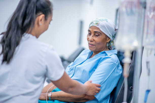Oncology patient A woman wearing a head scarf recovers from chemo treatment in the hospital. A doctor speaks with her and offers her support. chemotherapy drug stock pictures, royalty-free photos & images