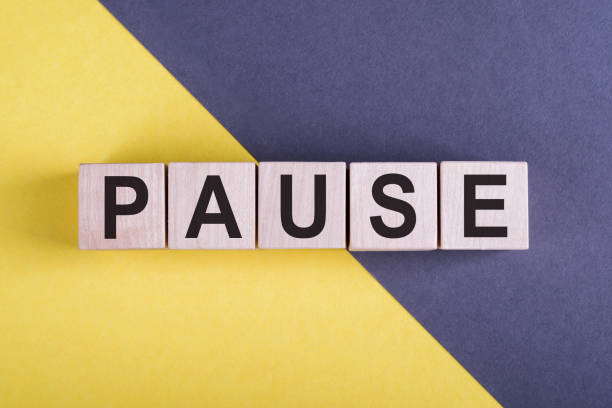 istock Word PAUSE on wooden cubes on yellow - gray background. 1332586040