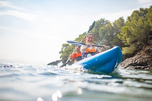 Water surface view of grinning male and female kayakers enjoying vigorous morning workout in Mediterranean Sea off the Costa Brava.