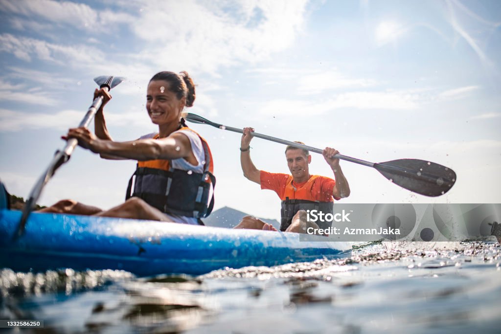 Action Portrait of Spanish Kayakers Enjoying Morning Workout Water surface level view of energetic male and female kayakers in 30s and 40s paddling past camera in Mediterranean Sea off the Costa Brava. Kayak Stock Photo