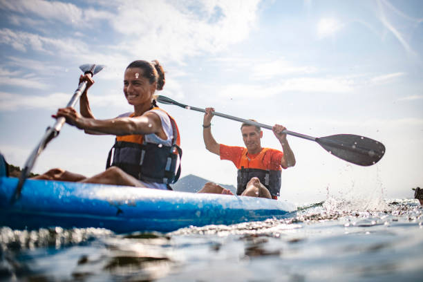 Action Portrait of Spanish Kayakers Enjoying Morning Workout Water surface level view of energetic male and female kayakers in 30s and 40s paddling past camera in Mediterranean Sea off the Costa Brava. using a paddle stock pictures, royalty-free photos & images