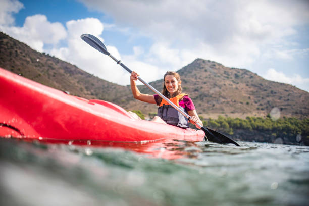 젊은 여성 카약 패들 링 과거 카메라의 동적 보기 - women kayaking life jacket kayak 뉴스 사진 이미지