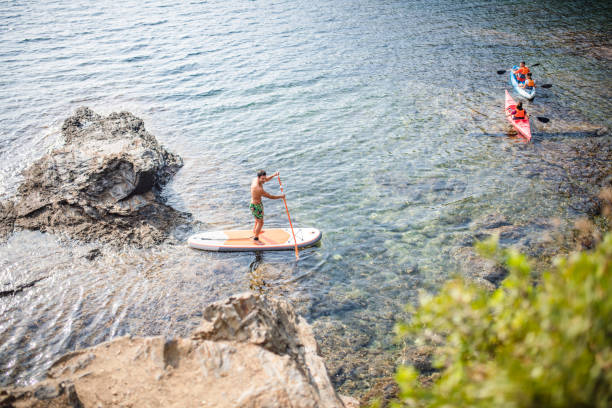 istock Paddleboarder and Kayakers Off Mediterranean Coastline 1332586316