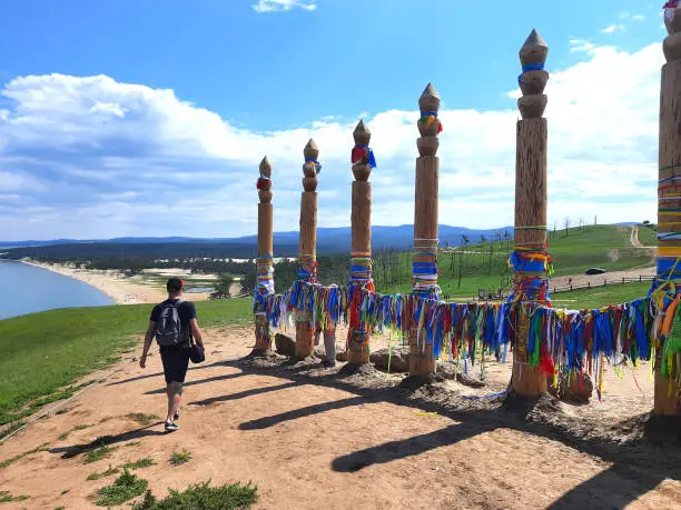 Russian tourist near hitching posts with ribbons of shamanism religion in Khuzhir, island Olkhon.