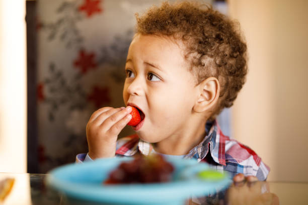istock Little boy eating strawberry 1332588682