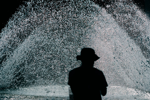 Silhouette of a man standing in front of a fountain