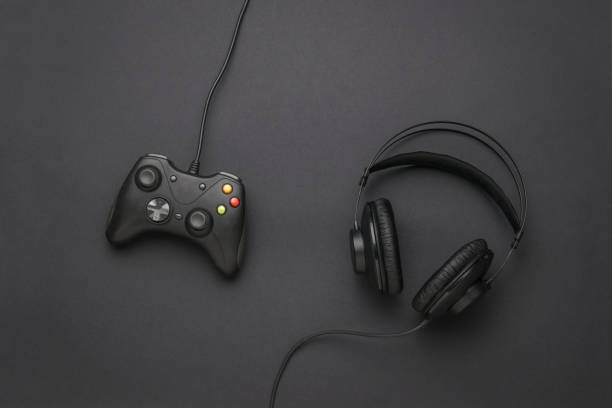 istock Wired headphones and a wired game console on a black background. Flat lay. Place for text. 1332601891